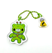 Green cartoon character keychain with a small yellow tag featuring a black figure on a white background