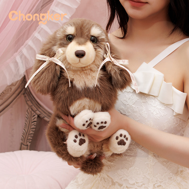Person holding a plush toy dog with a bow, wearing a white lace dress, against a soft pink background.