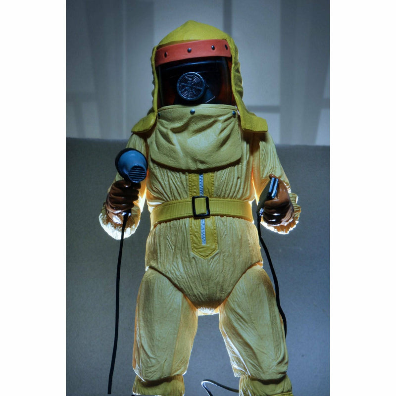 Person wearing a yellow hazmat suit with a helmet holding a blue device on a gray background