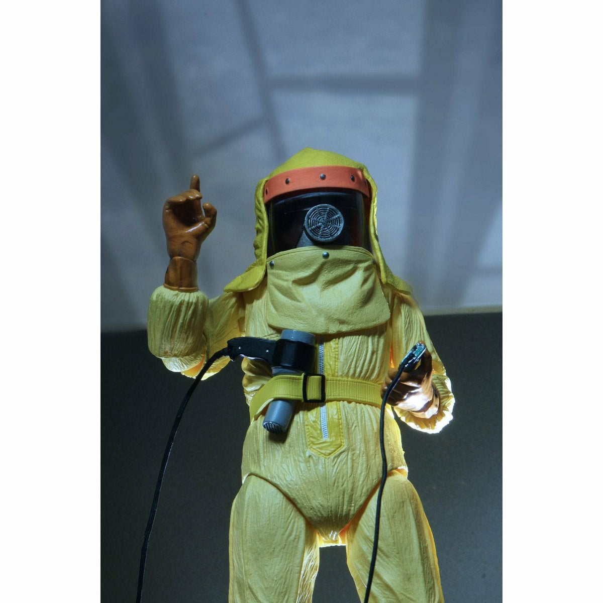 Figure in a yellow hazmat suit with a black helmet against a gray background