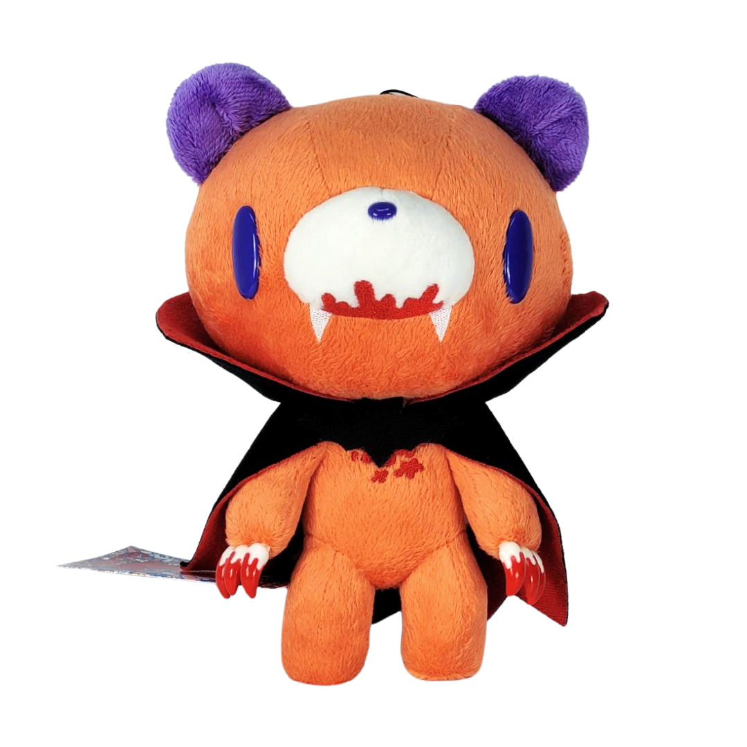 Orange plush toy with purple horns, blue eyes, and a black cape on a white background