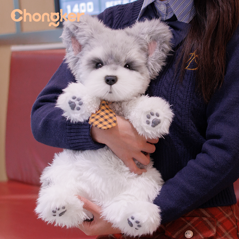 Person holding a plush toy dog with a bow tie, wearing a blue sweater.