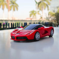 Red toy sports car on a reflective surface with blurred background