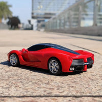 Red toy sports car on a textured surface with a blurred background