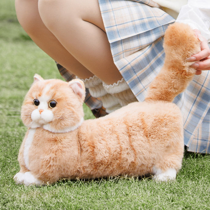 Plush cat toy on grass with a person in plaid skirt and white shirt in the background, featuring the brand 'Changker'.