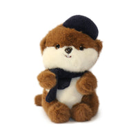 Plush toy otter wearing a navy hat and scarf on a white background