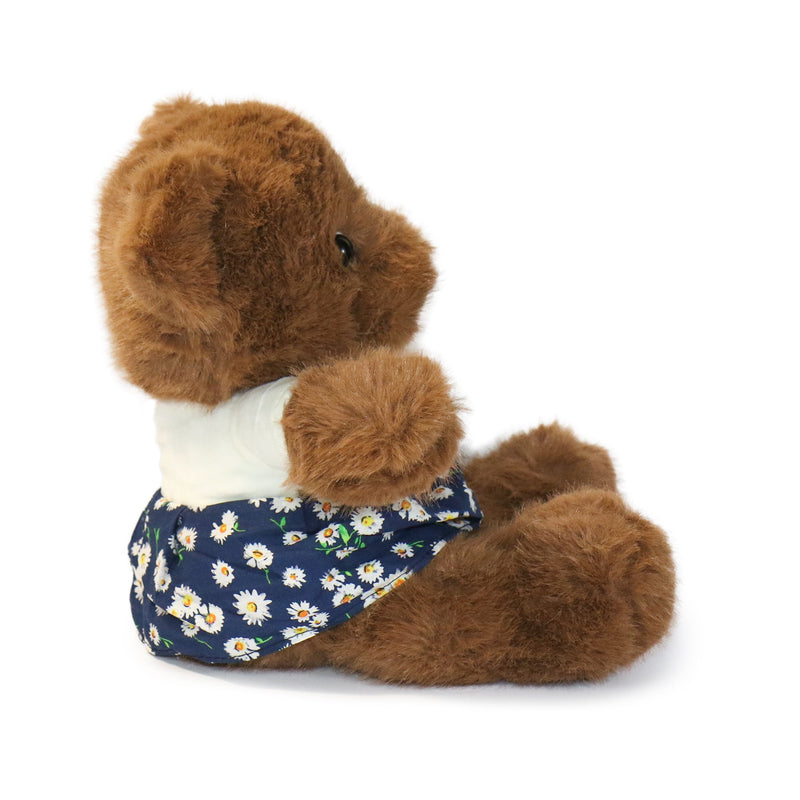 Brown teddy bear wearing a navy floral dress on a white background