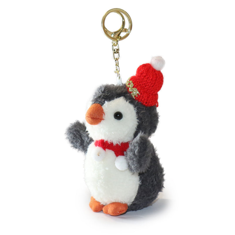 Plush penguin keychain with a red hat on a white background