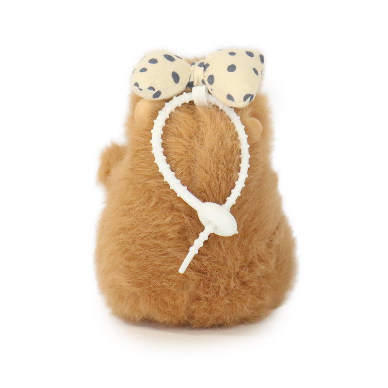 Plush toy resembling a cat with a polka dot bow on a white background