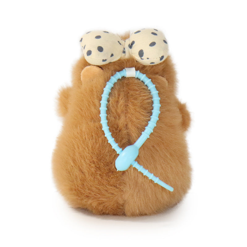 Plush toy resembling a hamster with polka dot eyes and a blue headband on a white background