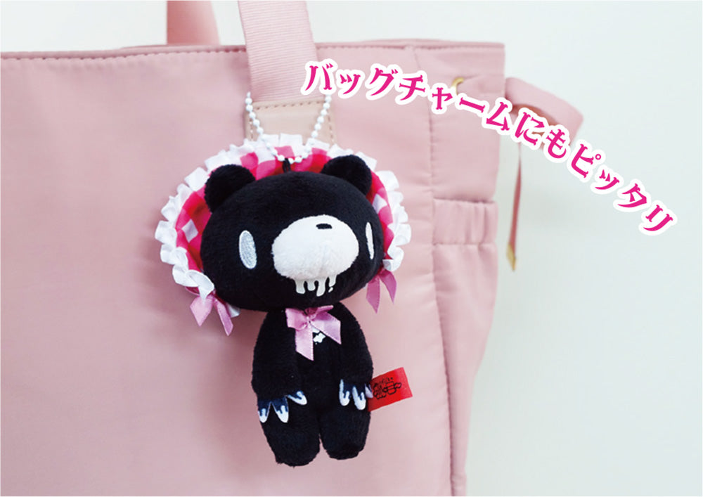 Black plush bear charm with pink accents on a pink bag