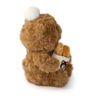 Brown teddy bear with a white ball on its head against a white background