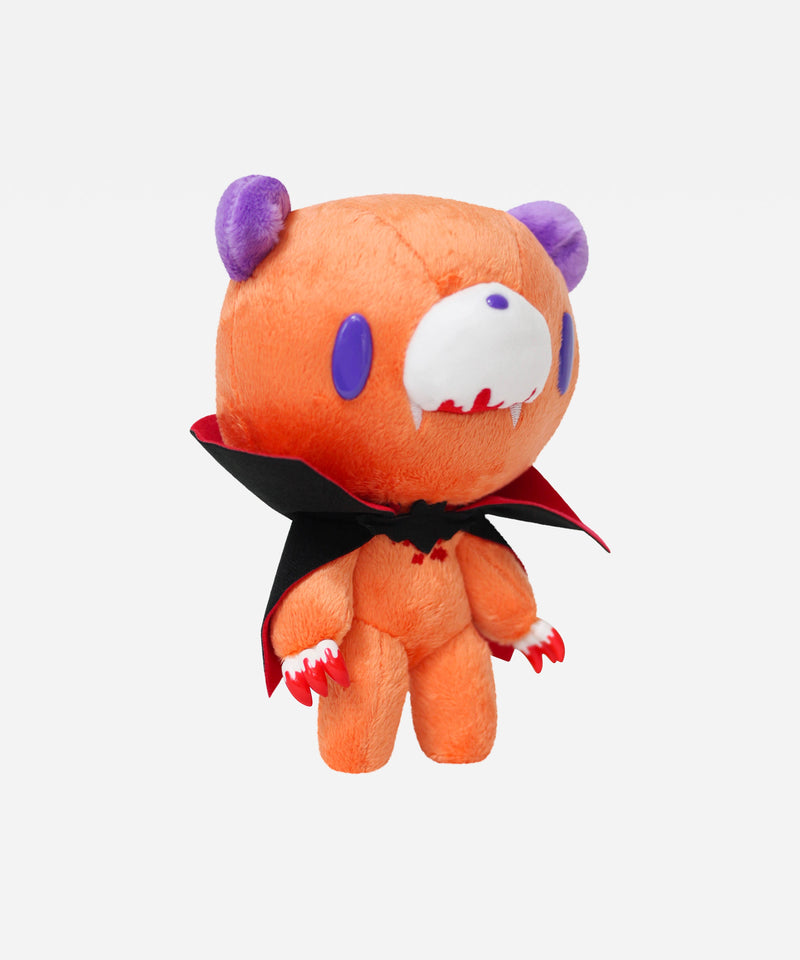 Orange plush toy with purple horns and a black cape on a white background