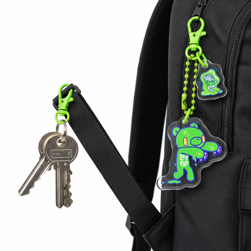 Green bear-shaped keychain with keys attached to a black backpack strap.