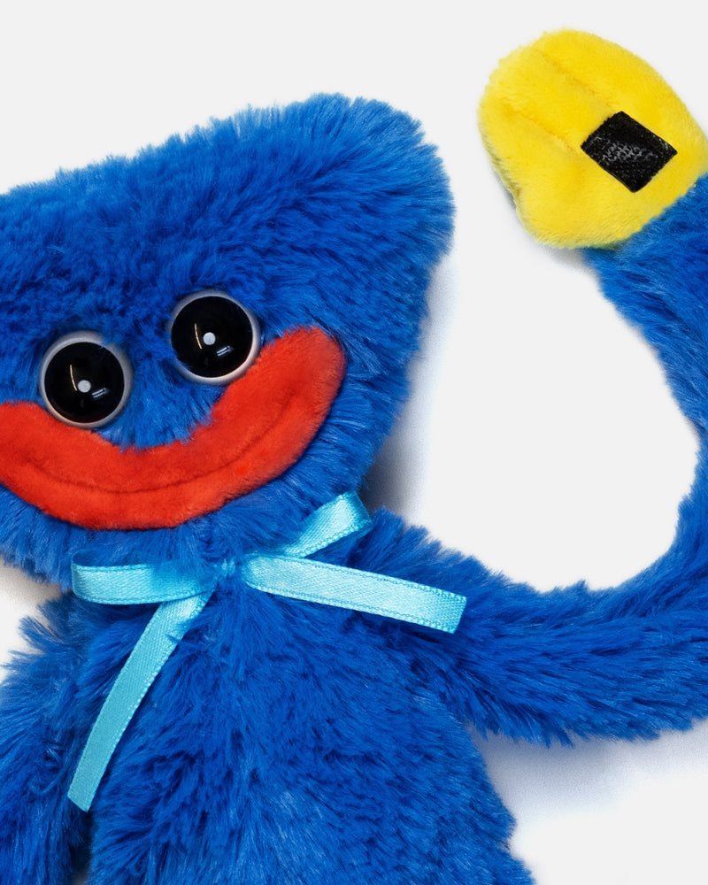 Blue plush toy with a red mouth and yellow tag on a white background