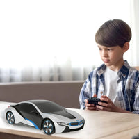 Young boy playing with a BMW i8 remote control car, enjoying realistic driving experience.