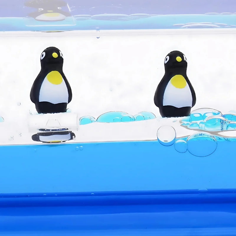 Close-up of penguins floating in a blue liquid motion toy, ideal for relaxation and decor