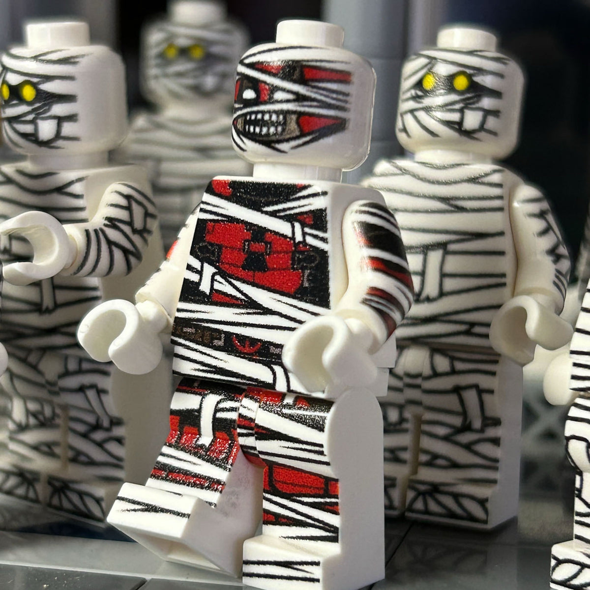 Toy mummy figures with a central figure holding a red '3' sign.