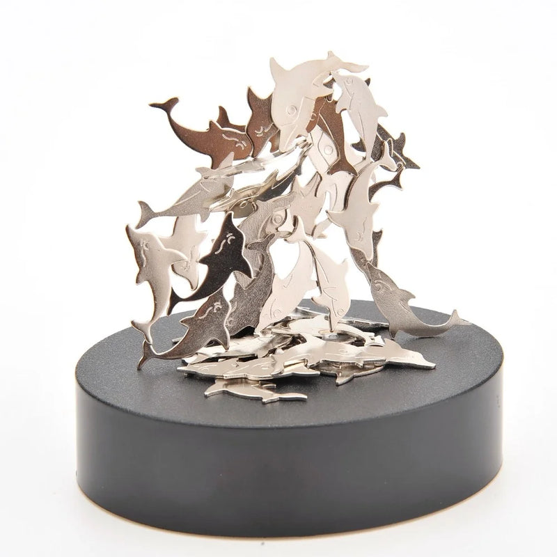 Stacked dolphin-shaped metallic pieces arranged artistically on a black magnetic platform.