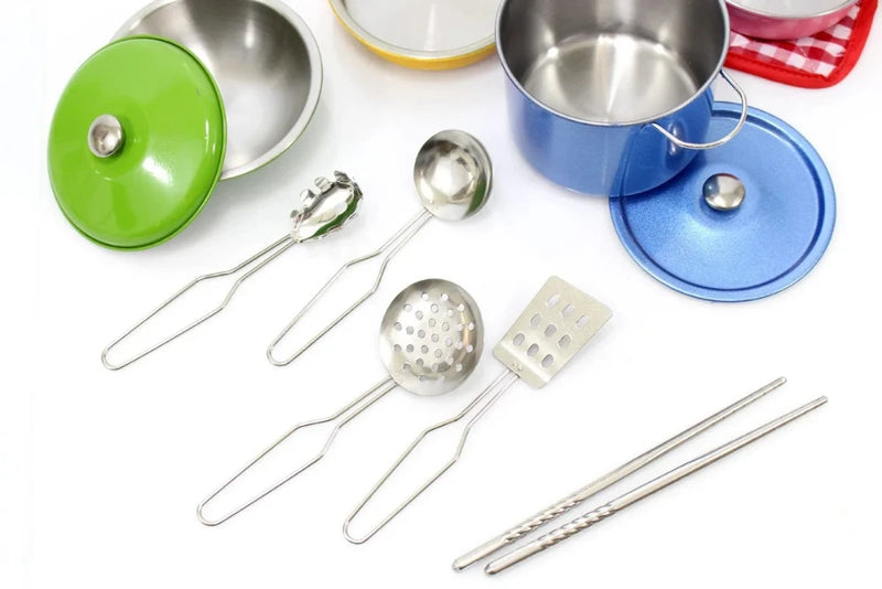 Green and yellow toy pans alongside cooking tools like spatula and ladle for children's kitchen play.
