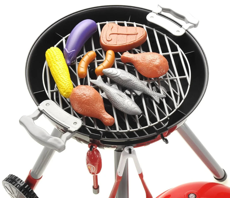 Close-up of toy BBQ grill with assorted pretend food including steak, fish, and vegetables