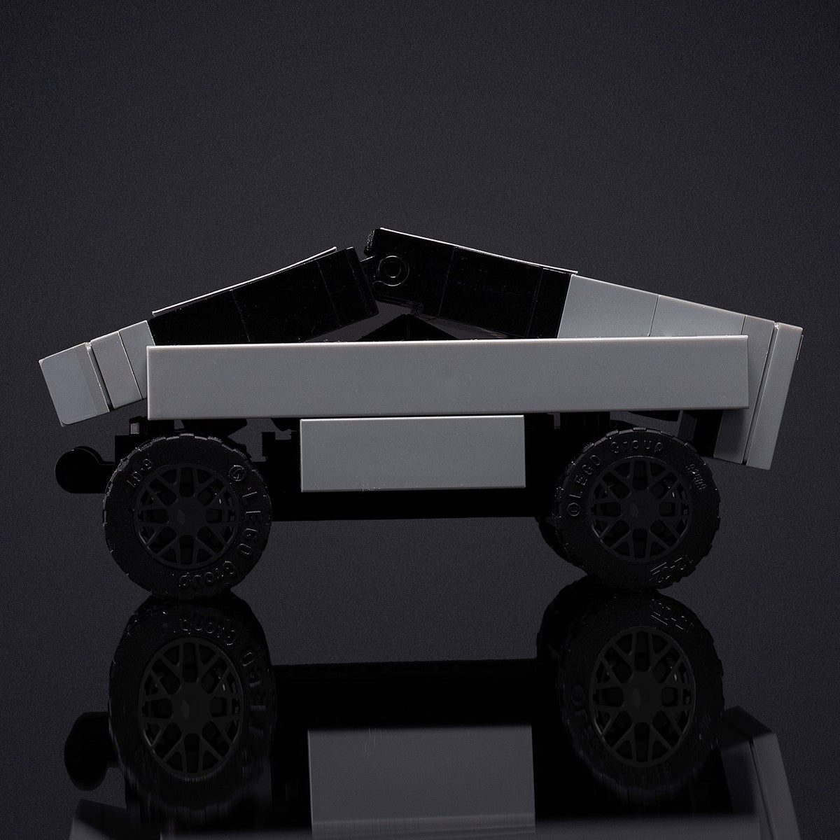 Toy truck made of interlocking bricks on a reflective surface with a dark background
