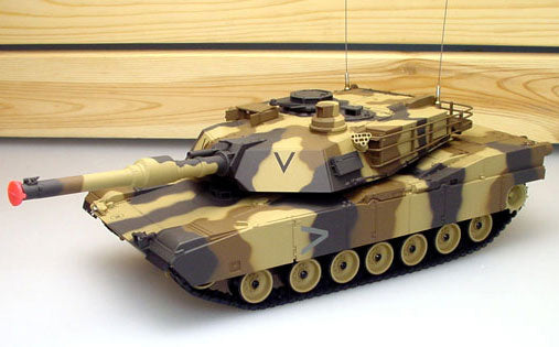 Camouflage toy tank on a white surface with a wooden background