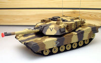 Camouflage toy tank on a white surface with a wooden background