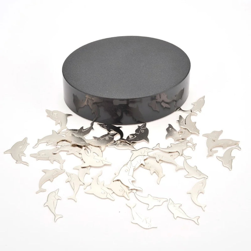 Black magnetic platform with scattered dolphin-shaped pieces for building creative sculptures.