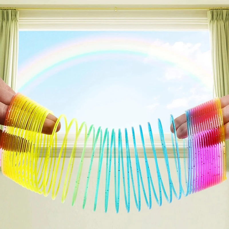 Hands stretching a rainbow magic spring toy in front of a window with a rainbow background