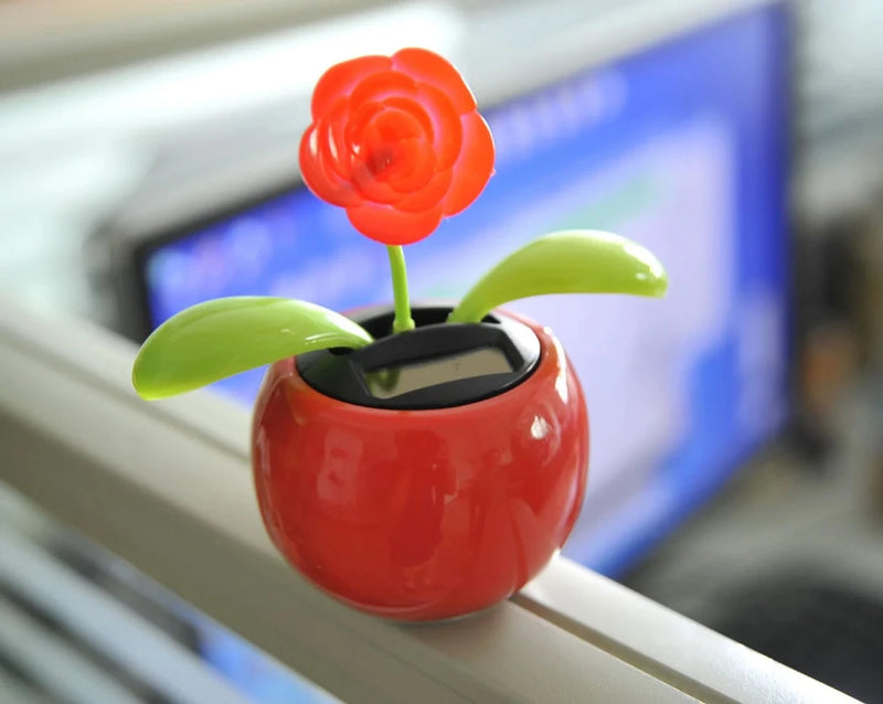 Solar powered flower toy with red flower and green leaves on office desk, adds a touch of nature indoors.