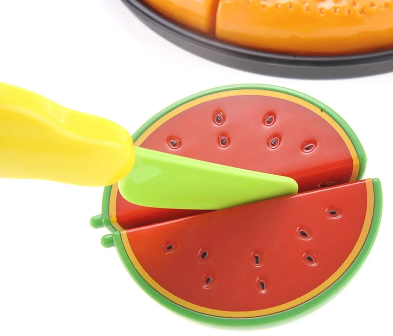 Toy watermelon being sliced with a green toy knife, part of a kids' cutting food play set.